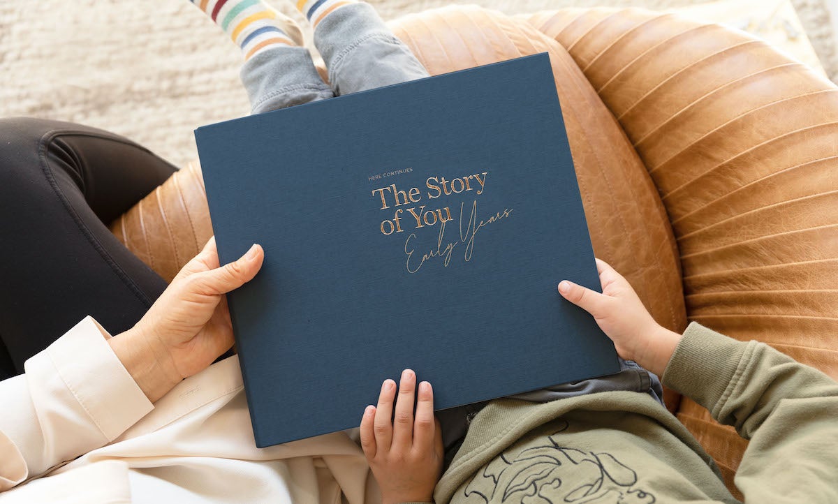 Overhead photo of parent and toddler both holding Artifact Uprising Early Years Childhood Memory Book