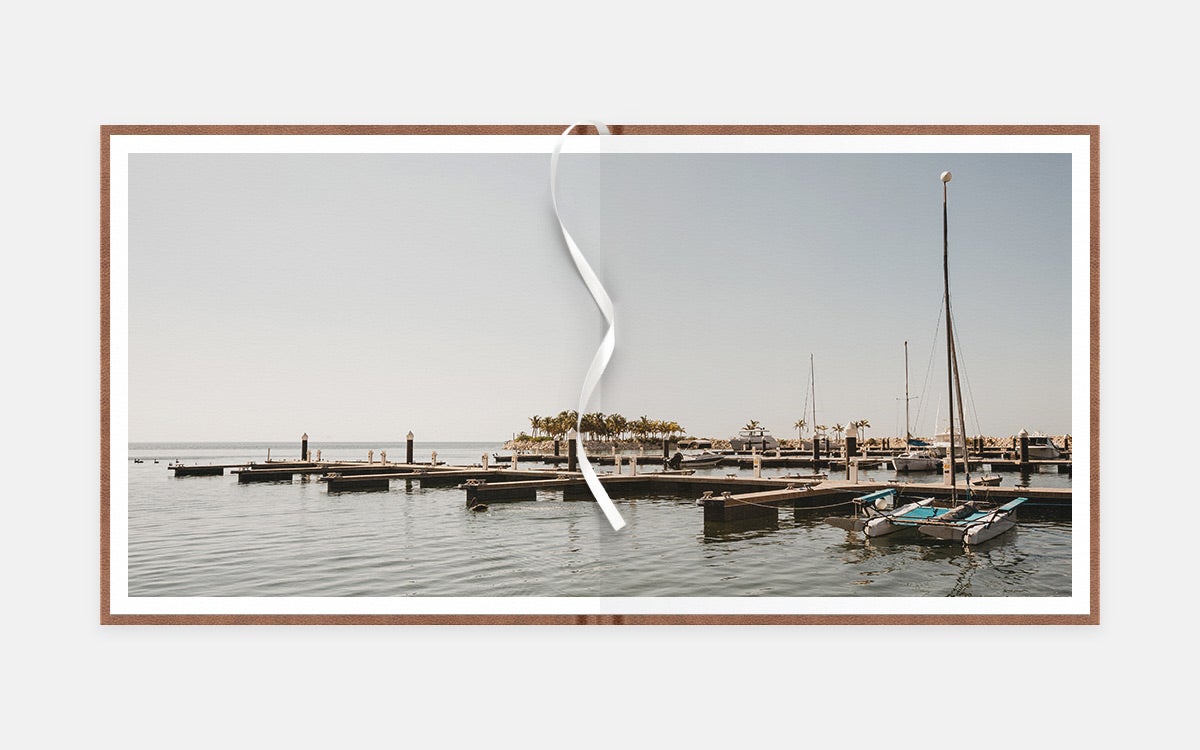 Two-age panoramic album spread of small sailboats at a dock