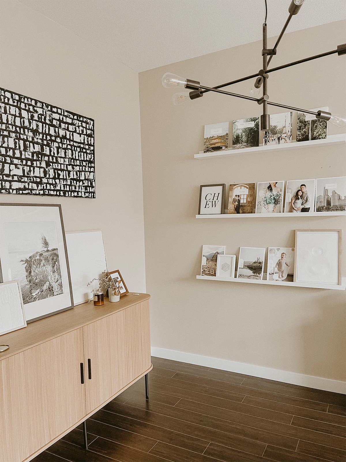 Frames, styling objects, and photo books on three floating ledges next to media console with large frame on it