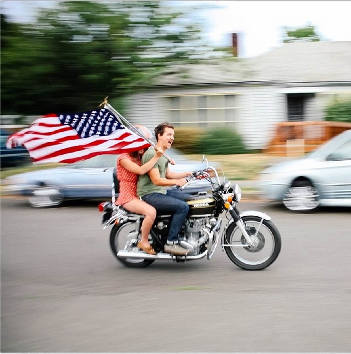 Motion blur photo of couple riding motorcycle holding USA flag