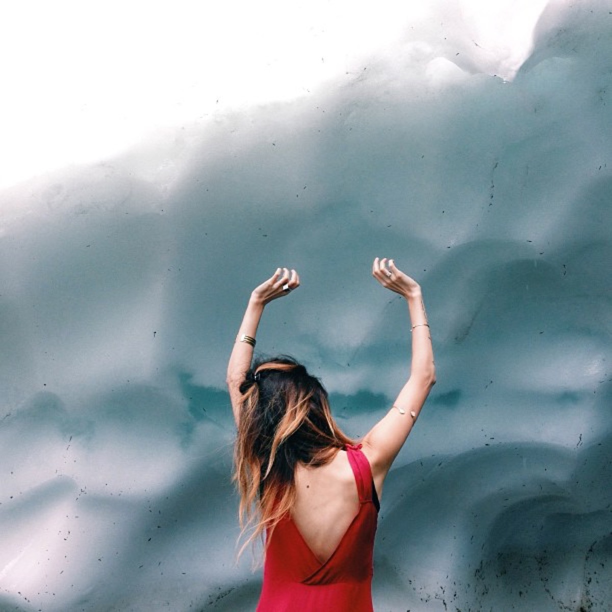 Bethany Marie photo of the back of a woman in a red dress facing a textured wall