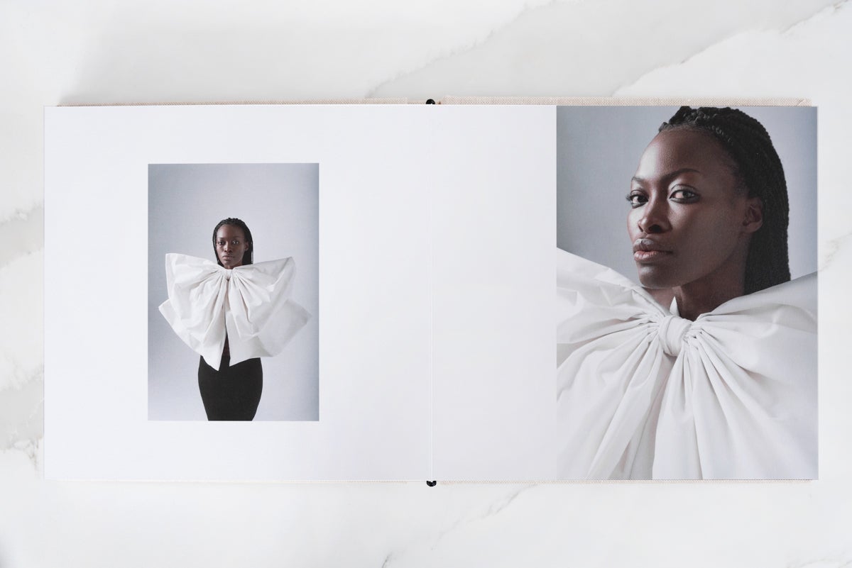 Artifact Uprising Layflat Photo Album opened to photo of woman wearing large white bow on left page and zoomed in portrait of same woman on right page