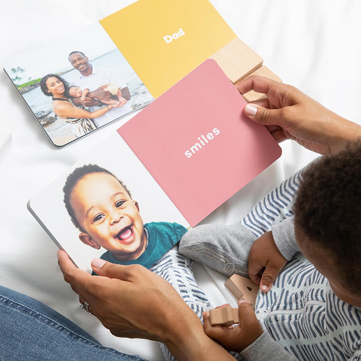 Mother and child reading baby board book opened to a page with the word smiles