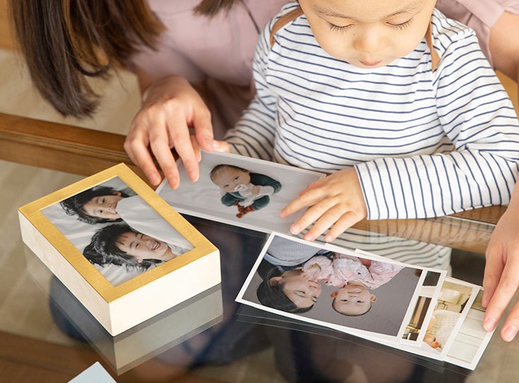 Mom and little boy choosing family photos to place inside Artifact Uprising Brass & Wood Display Box