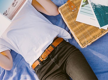 Woman lying on blanket reading softcover photo book by artifact uprising