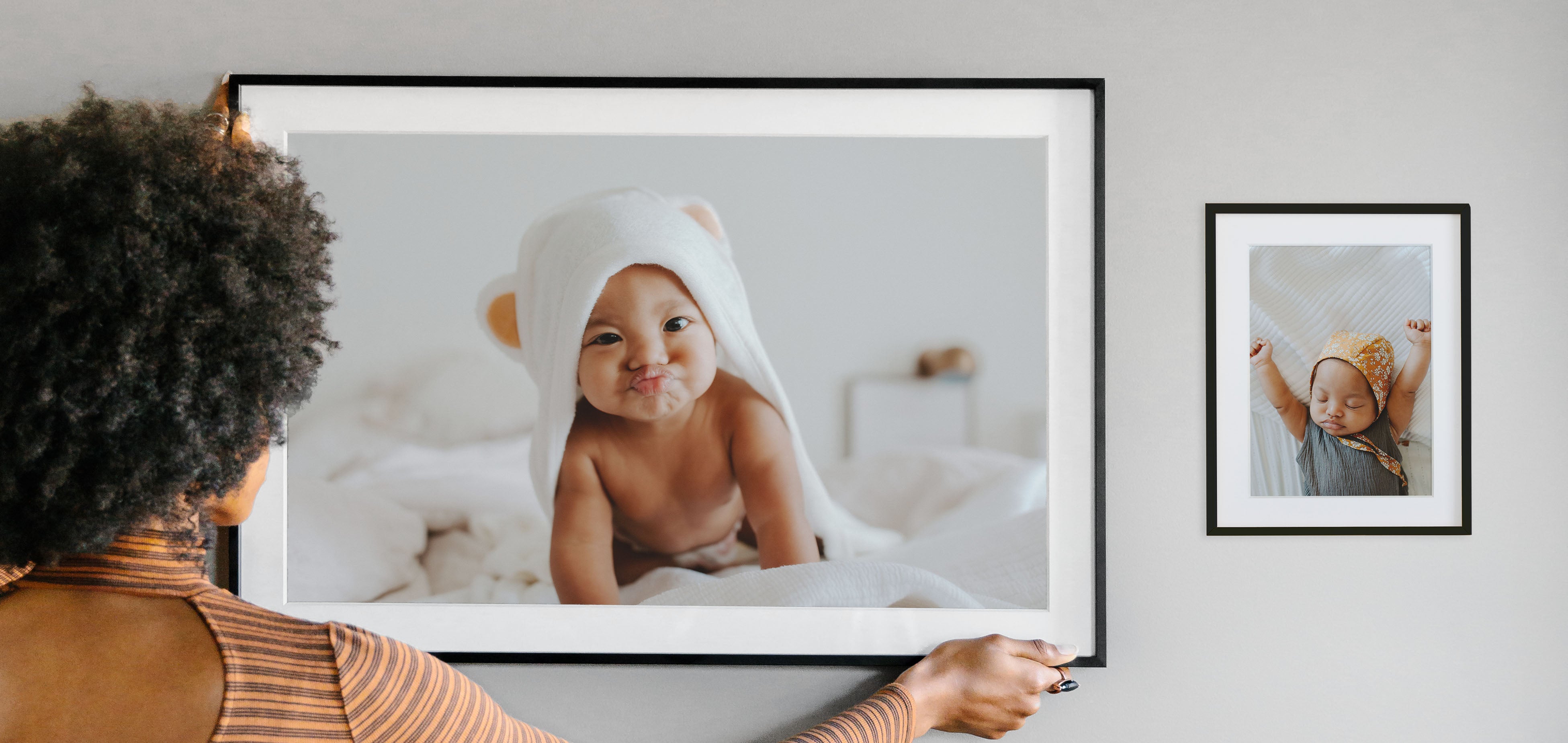 Woman hanging frame up to complete gallery wall idea