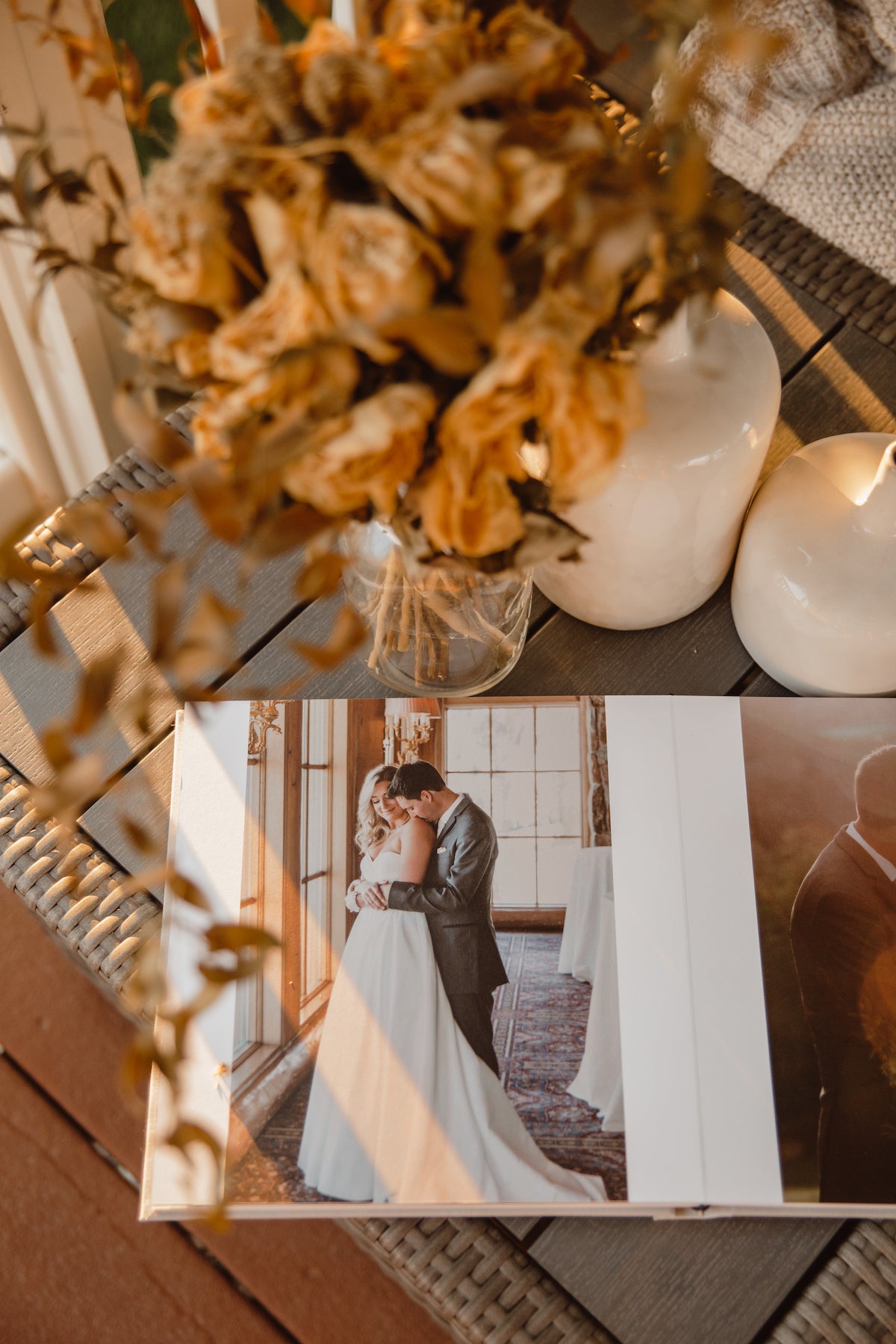 Overhead photo of dried botanicals in glass vase on side table next to Artifact Uprising Wedding Layflat Photo Album