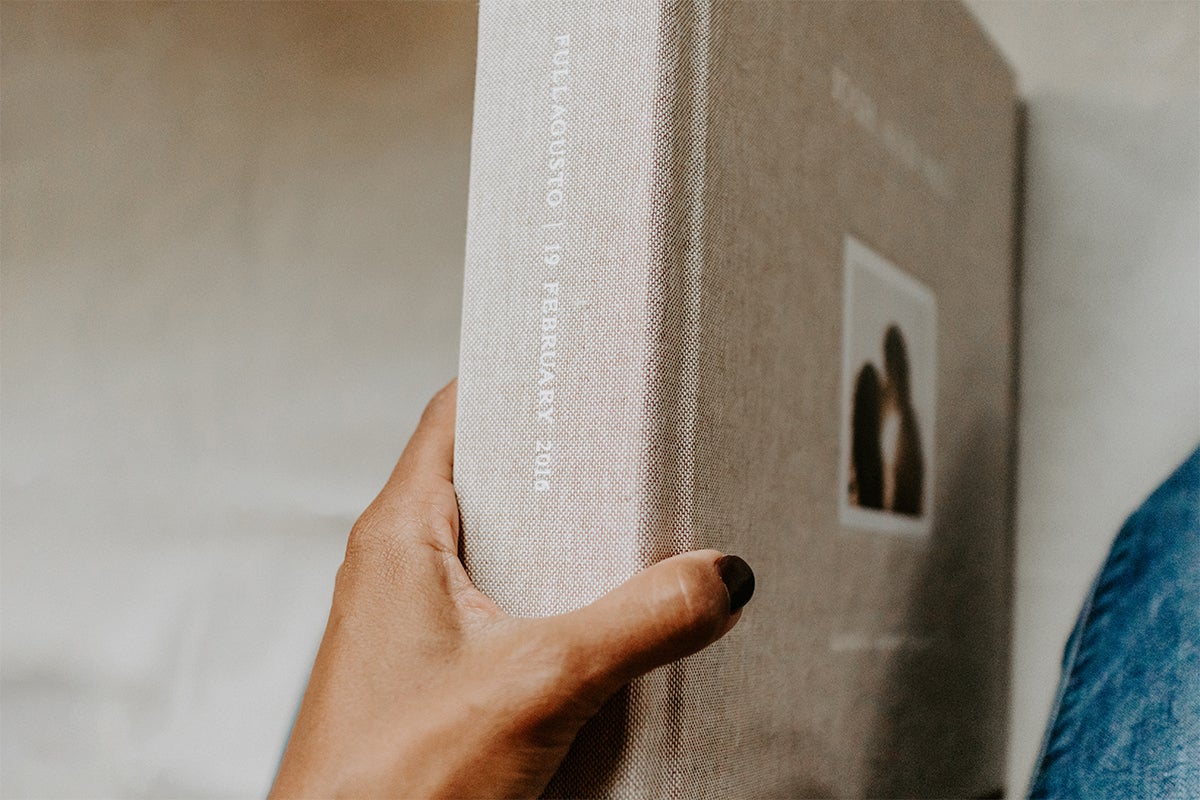 Woman's hands holding photo book by the spine