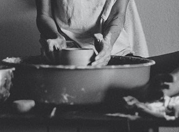 Woman throwing pottery cross-legged at the wheel