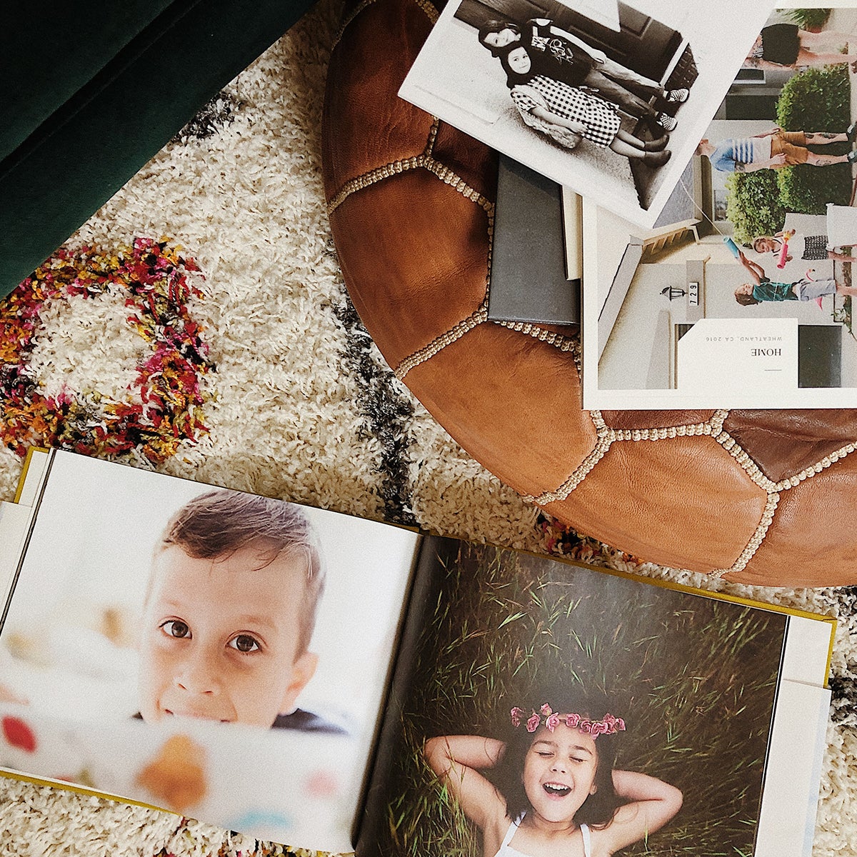 Stack of Artifact Uprising photo books on ottoman with one open on floor