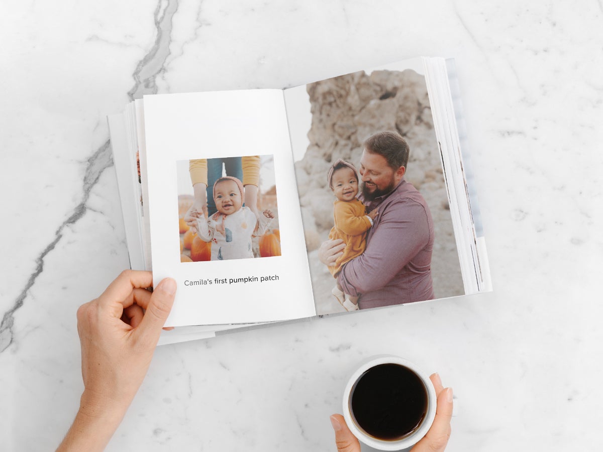 Hardcover photo book opened to photo of baby in pumpkin patch