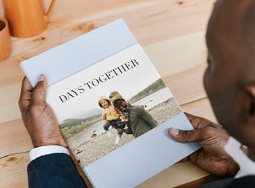 Man holding up family photo album with father and son on the cover