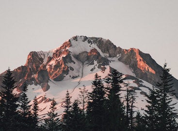 Sun kissing the top of a snowy mountain peak