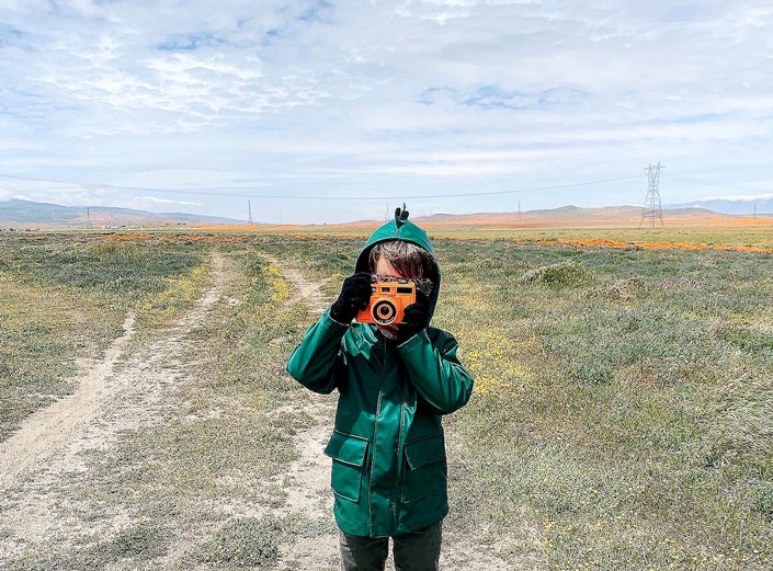 Little boy in open clearing holding toy camera