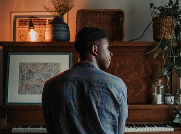 Man sitting at piano with back turned to camera