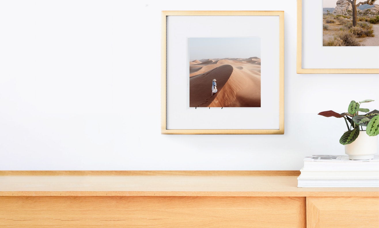 Two modern metal frames in brass on a wall above a credenza