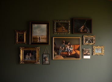 Gallery wall on dark olive green wall filled with family photos in gold and brass frames and an Artifact Uprising Gallery Frame in Walnut