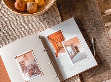 Photo prints strewn on table next to scrapbook in progress