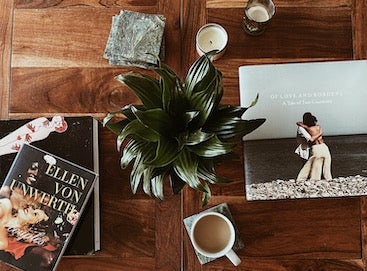 Artifact Uprising Hardcover Photo Book titled Of Love & Borders on coffee table next to other books