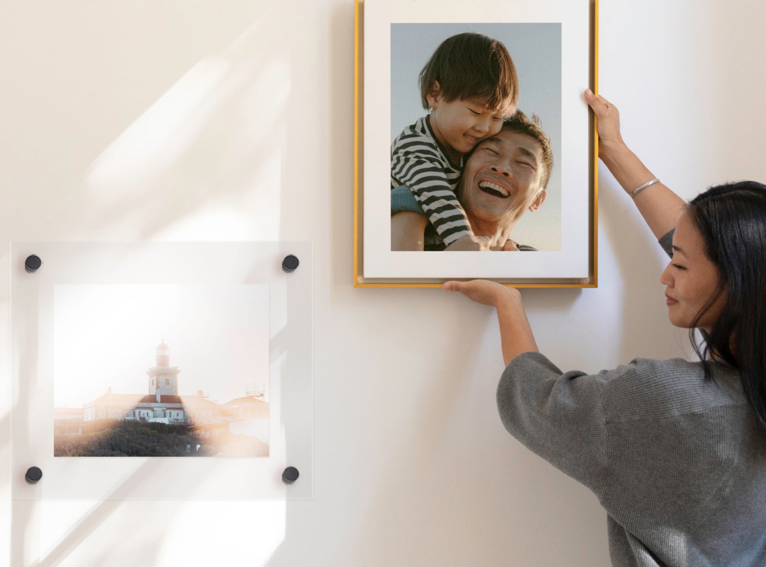 Woman hanging large portrait of swaddled newborn baby up on wall