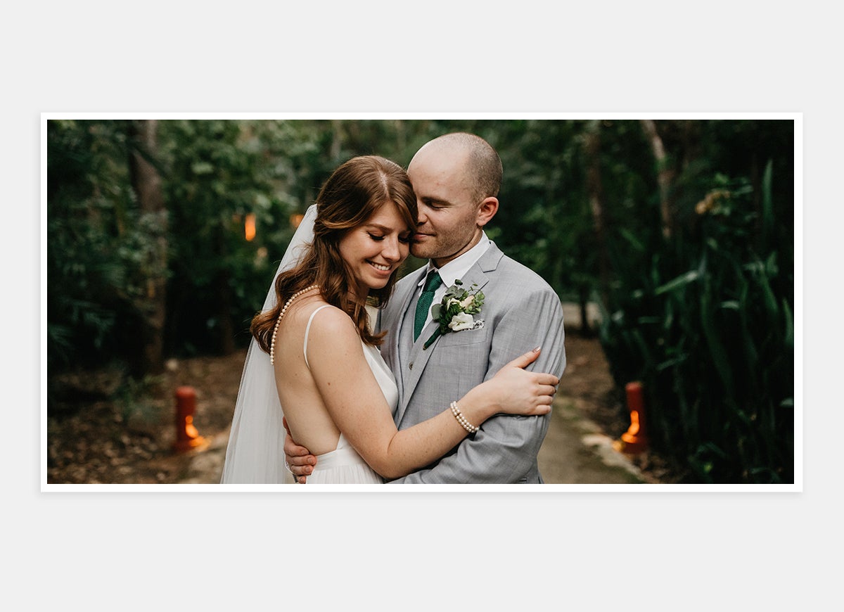 Two-page photo in wedding album of bride and groom embracing in front of beautiful backdrop