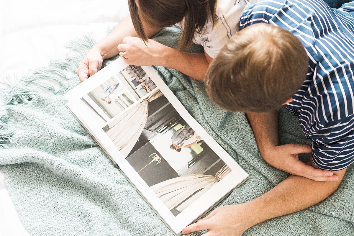 Couple flipping through detail shots in wedding photo book